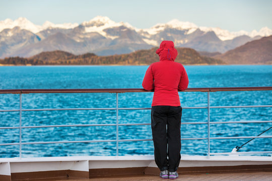 Alaska cruise travel tourist woman watching nature landscape from boat standing in cold morning weather with winter jacket in inside passage, Glacier Bay, USA.