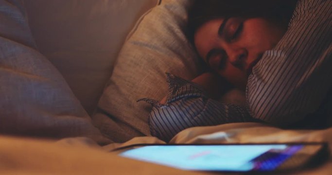 Woman Sleeping with Lights on at Night. SLOW MOTION 4K DCi. Young woman fell asleep while using digital tablet. Tired person.