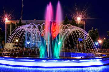 A beautiful illuminated city fountain Flower of a tulip at night. View of the town Pokrov in Ukraine, 2017
