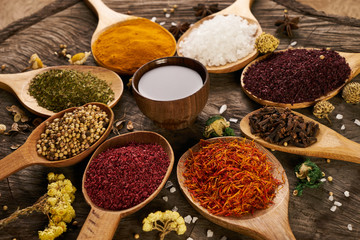 Spices in wooden spoons and bowl with olive oil