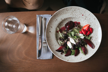 Close up photo of salad with knife and fork on table in restaurant. Photo of salad and glass of water on table at cafe