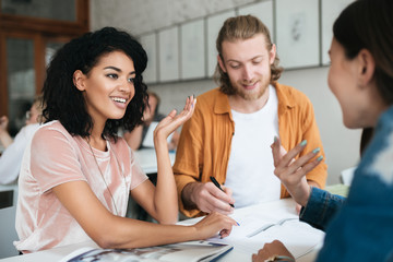Portrait of young group of people working together in office. Group of students studying together in classroom. Two pretty girls happily talking and discussion something together