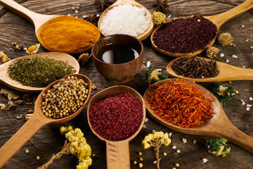Spices in wooden spoons and bowl with olive oil