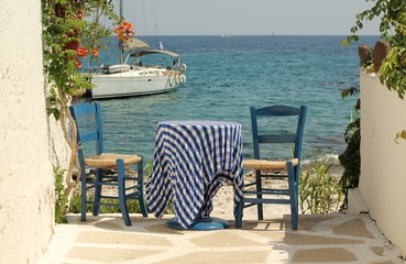 Traditional Greek blue table and chairs by the Aegean sea, Aegina island
