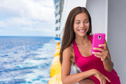 Cruise ship woman using mobile phone on travel vacation at ocean. Asian girl texting sms on boat wifi cellular data cellphone service on tropical holidays. Internet on international seas concept.