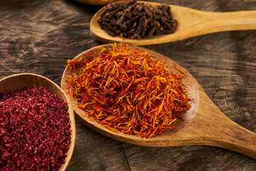 Colorful spices in wooden spoons on dark wooden background