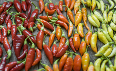 Colorful chilli peppers on wooden table. High angle view and selective focus