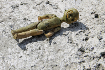 Abandoned old broken doll on grey concrete floor