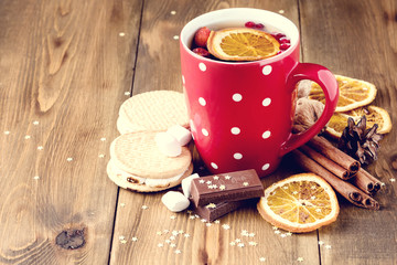 Red cup of hot tea with orange and berries Christmas winter beverage Christmas food concept Wooden background Cinnamone sticks Cookies Toned Copy space