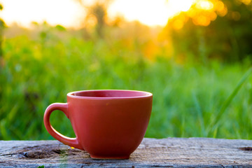 Morning cup of coffee on wooden table at sunrise