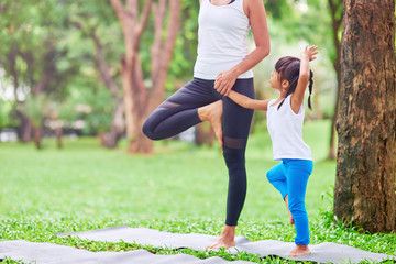 Pleasant caring mother teaching her little daughter to practive yoga