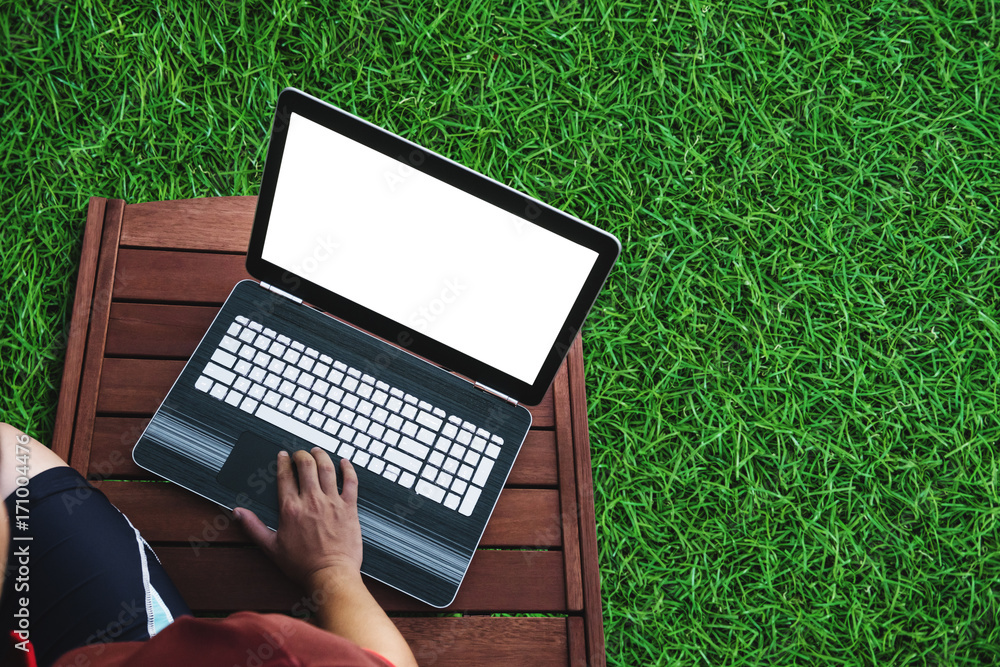 Poster a man using computer laptop on wooden chair with grass floor. clipping path computer screen