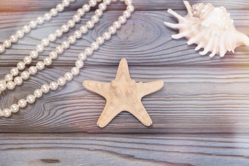 Fototapeta na wymiar A string of pearls, a starfish, a seashell on a wooden background