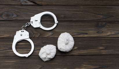 heroin. handcuffs on a wooden background