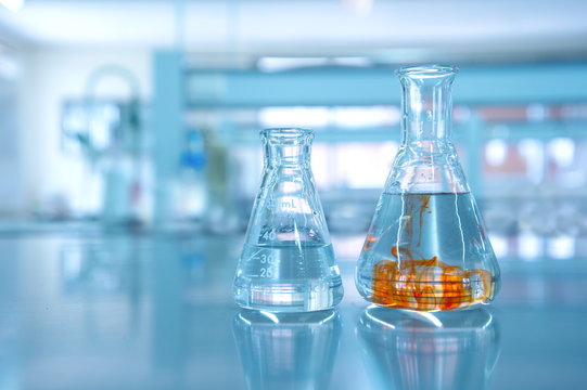 orange fluid in water in flask glassware in science chemical laboratory