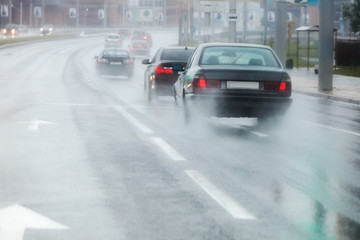 Fototapeta na wymiar traffic during bad weather. moving cars spraying rain puddles. 