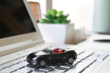 Business, finance, saving money, banking or car loan concept : Miniature car model on computer laptop