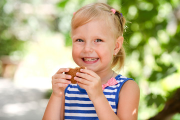 A little happy girl eats an avenaceous thin captain on nature.