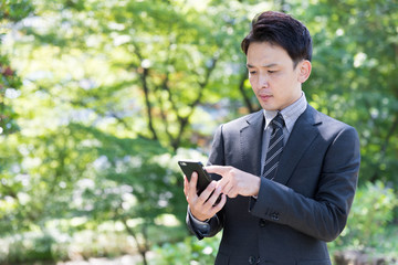 asian businessman using smart phone in park