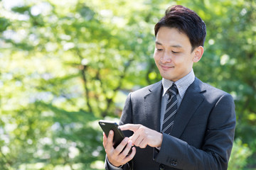 asian businessman using smart phone in park