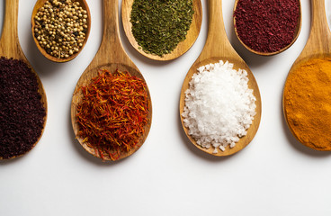 Spices in wooden spoons isolated on white background