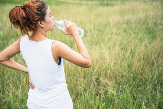 Asian women relax in the holiday. Drink Water on a green pasture.