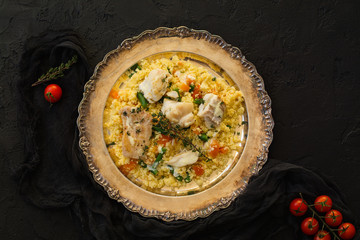 Couscous with fish and vegetables on stone table