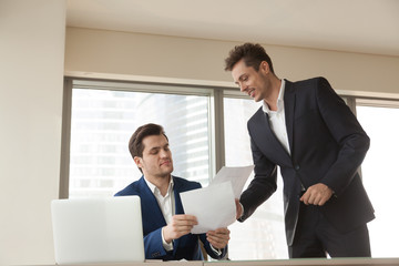 Company employee giving business papers to head manager for approval. Investment advisor presenting project documentation to client. Real estate agent showing apartments drawings to potential buyer