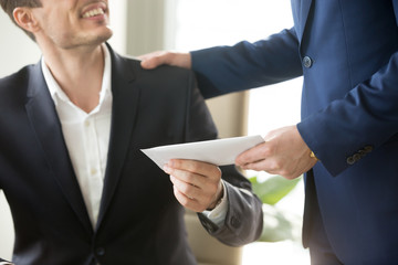 Company leader giving money bonus in paper envelope to happy smiling office worker, congratulating...