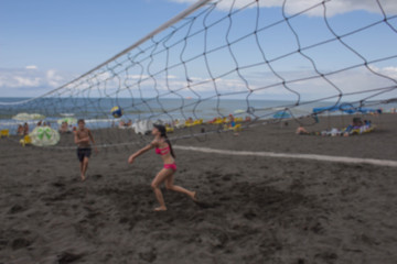 Blurred background. Teenage Friends Playing Volleyball On Beach