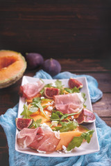 Ripe sweet melon with ham and arugula