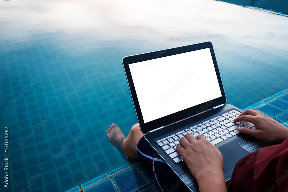 Poster a man using computer laptop, at poolside with dipping legs in the water. clipping path computer scre