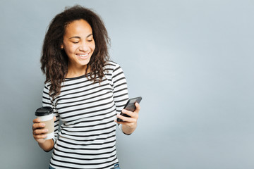 Positive delighted woman looking at her mobile phone