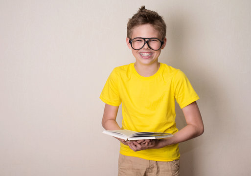 Health, Education And People Concept. Happy Teen Boy In Braces And Eyeglasses Holding A Book And Laughing.