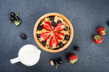 Granola and strawberry  in wooden  bowl,  on dark background. Top view. Breakfast with muesli and berries