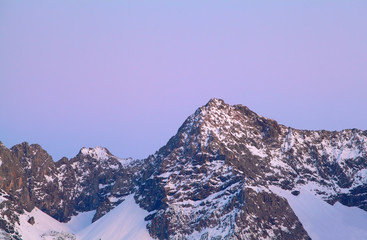 mountain peak in snow over purple sunset sky