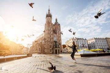 Fototapeta View on the central square and famous st. Marys basilica with pigeons flying during the sunrise in Krakow, Poland obraz
