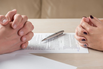 Hands of contractual parties, a woman and a man, signing a contract: business, premarital, loan, mortgage, credit, sales and purchase, investment agreement, divorce documents or other papers