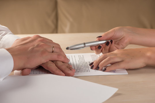 Hands of contractual parties, a woman and a man, signing a contract: business, premarital, loan, mortgage, credit, sales and purchase, investment agreement, divorce documents or other papers