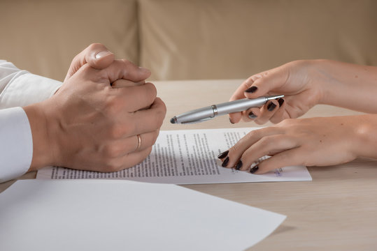 Hands of contractual parties, a woman and a man, signing a contract: business, premarital, loan, mortgage, credit, sales and purchase, investment agreement, divorce documents or other papers