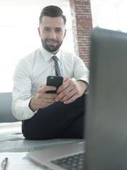 businessman holding a smartphone and looking at the camera