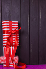 slide of gifts in a red and white wrapper against a black wooden fence.
