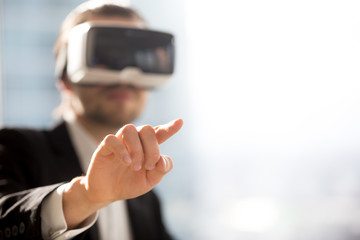 Businessman in VR glasses pointing finger in air. Office worker or CEO immersed in virtual reality, innovative method of managing business project through augmented reality. Close up. Space for text.