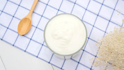 White yogurt and spoon on a wooden table.