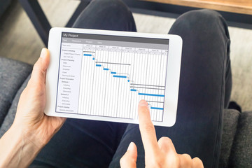 Project manager updating Gantt chart schedule, planning software, tablet computer