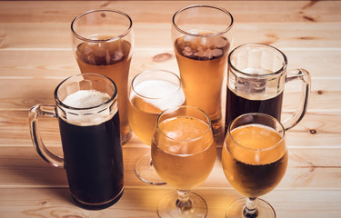 Beer glasses and beer mugs on wooden table. Selective focus. Vintage style