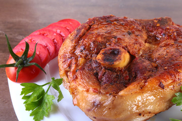 grilled pork chop with sliced tomato and sauce on wooden table.