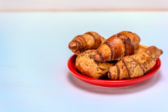 croissants on a wooden background on a red plate