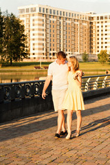  young family couple walking and hugging in the city park near the river