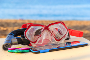 Mask for diving, a breathing tube, colored spinners and a tablet on a lounger on the beach and the...